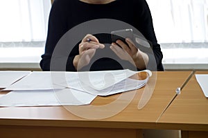 A woman is holding a pen and a smart phone in her hand
