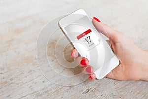 Woman holding phone in hand and looking at calendar