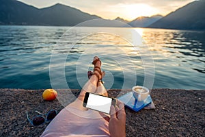 Woman holding phone lying on the pier