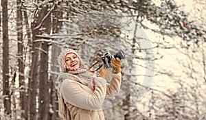 woman holding photo camera. taking picture in winter forest. Photographer photographing on snowy winter day. happy woman