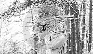 woman holding photo camera. taking picture in winter forest. Photographer photographing on snowy winter day. happy woman