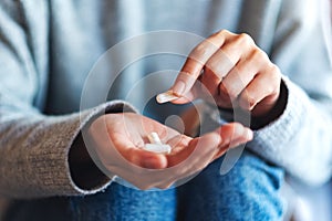 A woman holding and picking white medicine capsules in hand