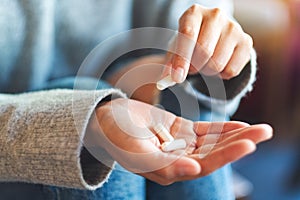 A woman holding and picking white medicine capsules in hand