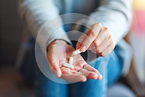 A woman holding and picking white medicine capsules in hand