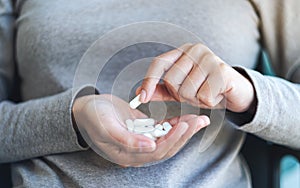 A woman holding and picking white medicine capsules in hand
