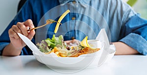 A woman holding a piece of french fries and fish and chips on table in the restaurant