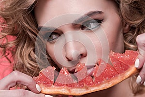 Woman holding piece of grapefruit isolated on pink