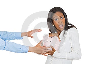 Woman holding piggy bank, frustrated trying to protect her savings