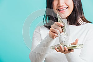 Woman holding piggy bank on hands and putting dollars money banknotes