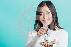 Woman holding piggy bank on hands and putting dollars money banknotes