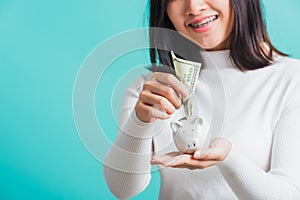 woman holding piggy bank on hands and putting dollars money banknotes