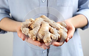 Woman holding pile of ginger roots on light background, closeup. Natural antibiotic