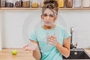 Woman holding pill and glass of water in hands taking emergency medicine, supplements or antibiotic antidepressant
