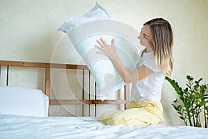 Woman holding a pillow while sitting on her bed