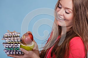 Woman holding pills and fruits. Health care