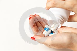 Woman holding pills on hand. Medicine and health care concept. Hand spilling pills for the pain of a bottle on white background