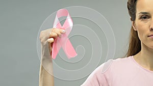 Woman holding pink ribbon, breast cancer awareness, need for regular examination