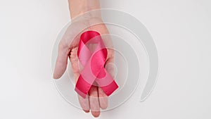 A woman is holding a pink ribbon on a white background. Symbol of the fight against breast cancer.