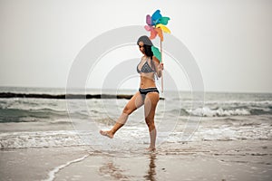 Woman Holding Pinwheel Toy While Walking At Beach Against Sky