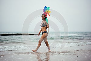 Woman Holding Pinwheel Toy While Walking At Beach Against Sky