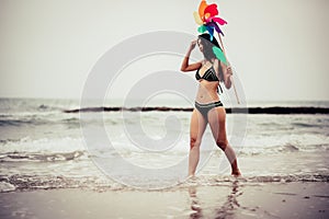 Woman Holding Pinwheel Toy While Walking At Beach Against Sky