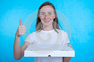 Woman holding pizza boxes over isolated blue wall with happy expression