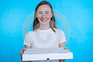 Woman holding pizza boxes over isolated blue wall with happy expression