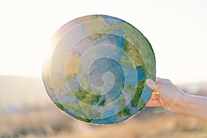 Woman holding planet in hands against green spring background. Earth day
