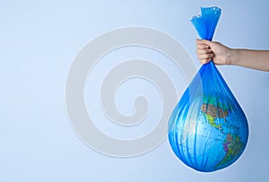 Woman holding plastic bag with globe and space for text on light background, closeup. Environmental conservation