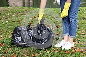 Woman holding plastic bags with garbage in park, closeup