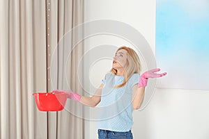 Woman holding plastic basin under water leakage from ceiling