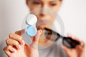 Woman holding plastic container with contact lenses