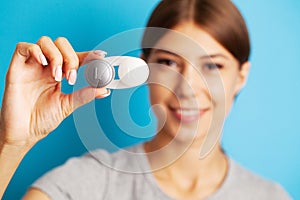 Woman holding plastic container with contact lenses