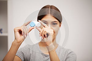 Woman holding plastic container with contact lenses