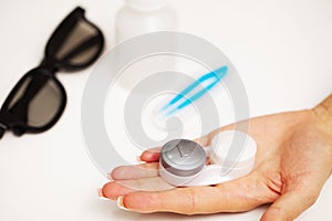 Woman holding plastic container with contact lenses