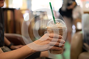 Woman holding plastic glass of iced coffee with milk