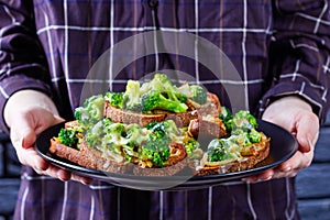 Woman holding a plate of broccoli melt sandwiches