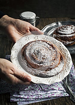 Woman holding plate with cinnamon roll