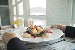 A woman holding a plate of mixed fruits salad