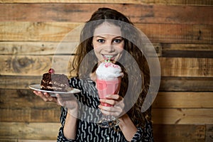 Woman holding plate of pastry and drinking milkshake with a straw