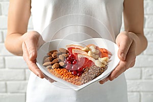 Woman holding plate with products for heart-healthy diet