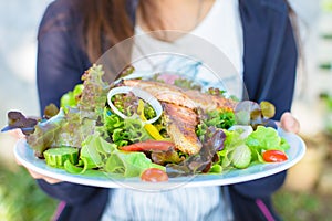 Woman holding a plate of salmon salad.