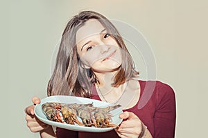 Woman holding plate with shrimps on white grey background