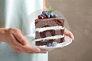 Woman holding plate with slice of chocolate sponge