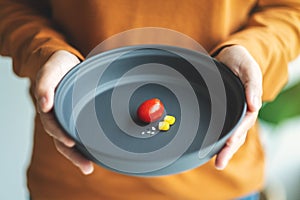 A woman holding a plate of small amount of food for diet concept