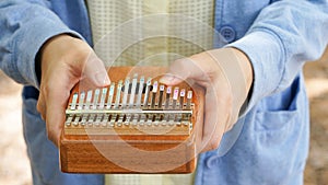 Woman holding play thumb piano or kalimba musical instrument