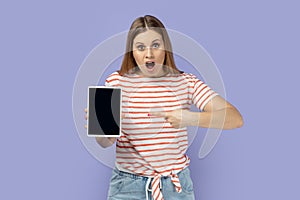 Woman holding pointing at tablet with empty display, mockup screen for your advertisement.