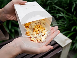 Woman holding popcorn cheese in a paper bag in the hand
