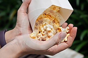 Woman holding popcorn cheese in a paper bag in hand