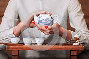 Woman holding porcelain teapot in front of the camera.